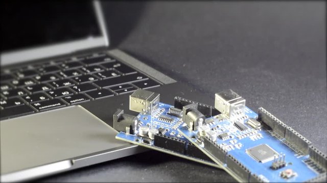 A man's hand takes a DIY board against a laptop background. Robototechnic, DIY, electronic. Mega board.