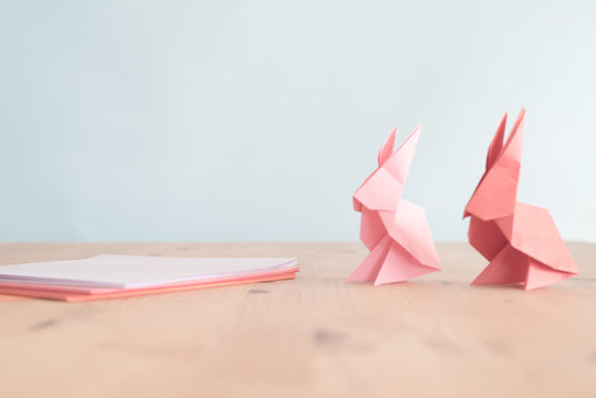 Pink and red origami easter bunnies on a wooden table