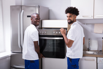 Two Male Workers Placing The Oven In The Kitchen