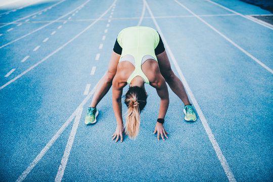 Young female athlete stretching on running track