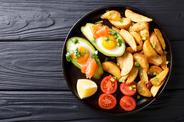 crockpot avocado stuffed with eggs and salmon, tomatoes and potato close-up on a plate. horizontal top view