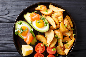 Delicious food: Baked avocado stuffed with eggs and salmon, fresh tomatoes and potato close-up. Horizontal top view