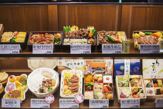 High angle view of a selection of Bento boxes with traditional Japanese foods on shelves.