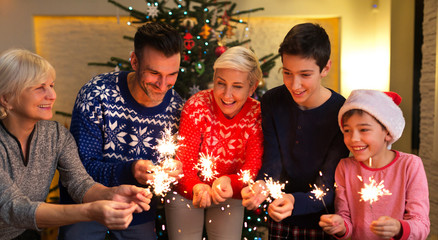Family with sparklers at Christmas time at home 