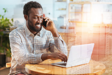 Video call. Delighted male keeping smile on his face and looking at computer while answering on...