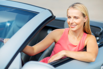 happy young woman driving convertible car