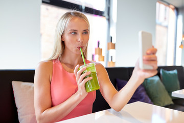 woman with smartphone taking selfie at restaurant