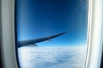 Window of aircraft wing with white cloud on sky