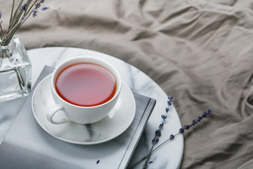 Cup of black tea on a book on the marble tray in bed at morning
