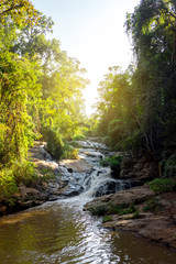 Obraz premium The beautiful waterfall in the national park in Thailand with lots of shade trees in the suny day.