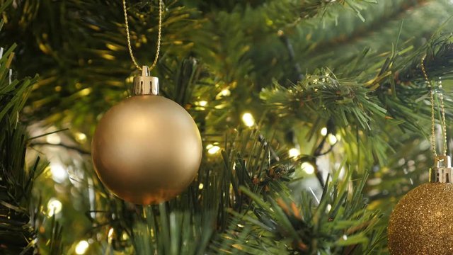 Bauble with fairy-lights on the artificial tree branch close-up UltraHD footage - Golden color Christmas ornament
