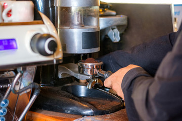 Man Barista making coffee grinding powder on coffee machine
