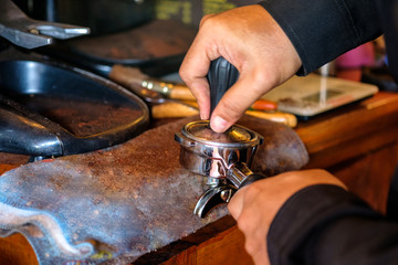 Hand barista tamper pressing powder coffee in grinder