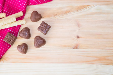 2497472 wooden light background chocolate candy heart and a gift wafer tubules