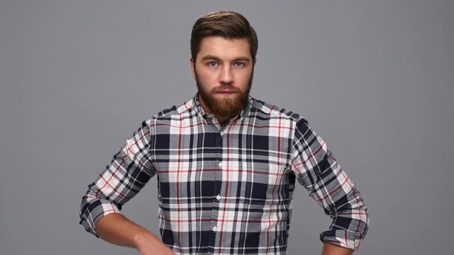 Mystery bearded man in shirt showing silence gesture over gray background