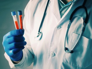 science, chemistry, biology, medicine and people concept - close up of male scientist or doctor holding test tube with blood sample making research in clinical laboratory