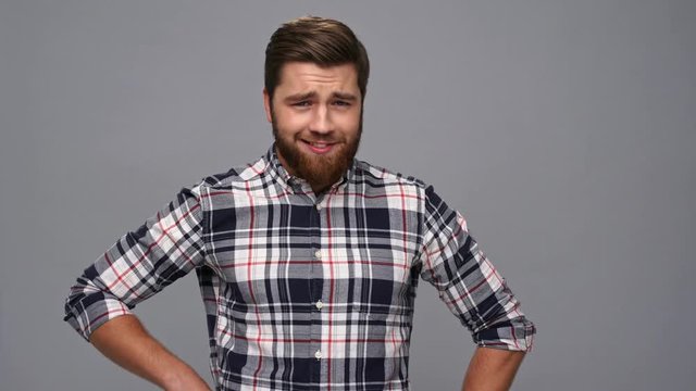 Funny cool bearded man in shirt posing and looking at the camera over gray background