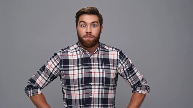 Pensive bearded man in shirt having idea and rejoice over gray background