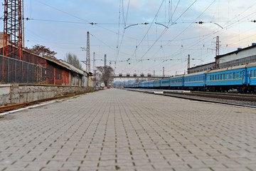 Fototapeta premium Railway station against beautiful sky at sunset. Industrial landscape with railroad, colorful cloudy blue sky. Railway sleepers. Railway junction. Heavy industry. Cargo shipping. Travel background