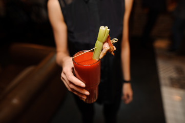 female in the black shirt holding a glass of alcoholic cocktail Bloody Mary