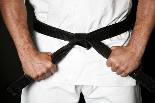Closeup of male karate or ju-jitsu fighter hands in white kimono and black belt