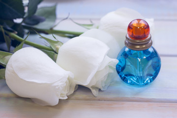 The concept of Love, Wedding, Proposal, Anniversary, St. Valentine's Day, Mother's Day with beautiful white roses and a bottle of parfume in a close up, light wooden background