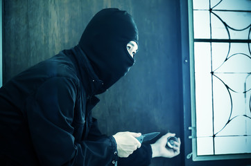 Asian robber or thief man in black hoodie jacket and mask with a knife wait for a victim in apartment. criminal and robbery for public safety concept.