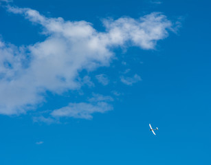 Obraz na płótnie Canvas A Glider flying in bleu sky with big white clouds. The glider is a plane that has no engine