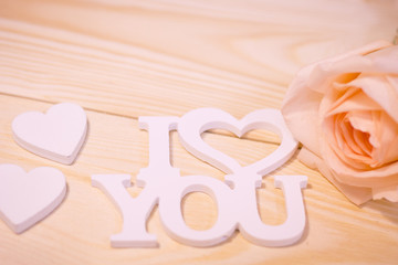 Concept of St.Valentine's Day, Love, Anniversary, Wedding with I Love You inscription and a beautiful cream rose on a wooden table, close up,