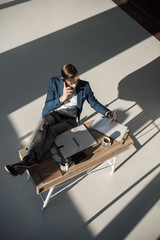 high angle view of businessman talking on smartphone while sitting at workplace
