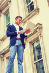Fototapeta premium Way to Success. African American college student studies in New York. Wearing blue blazer, white shirt, man stands outside vintage office building, works on laptop computer. Filtered effect.