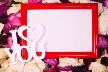 Concept of St.Valentine's Day, Love, Anniversary, Wedding with a blank red photo frame and I Love You inscription on red, pink and white rose petals, close up