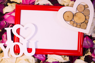 Concept of St.Valentine's Day, Love, Anniversary, Wedding with a blank red photo frame and I Love You inscription on red, pink and white rose petals, close up