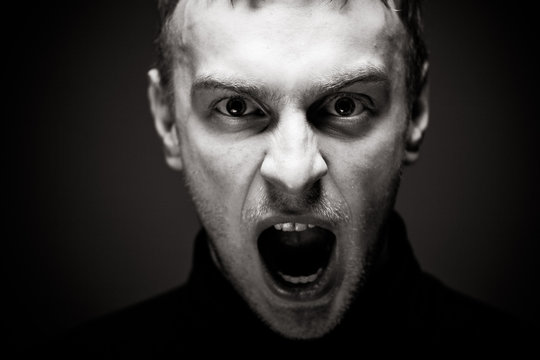 Angry man screaming. A man in a black shirt.