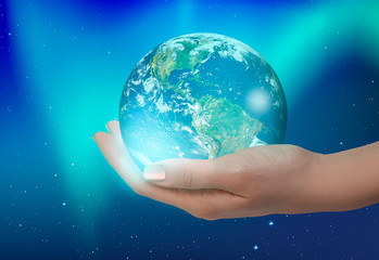 Woman holding glass globe on her hand with aurora "Elements of this image furnished by NASA"