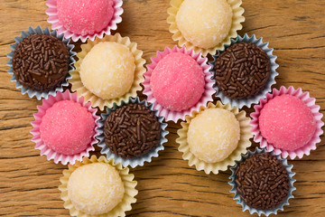 Brigadeiro Beijinho and Bicho de Pe: sweets from Brazil. Child birthday party. Overhead of candy ball on rustic wood table.
