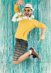 Man in green and yellow clothes, sunglasses and Hawaiian necklace. Carnival, New Year's Eve,...