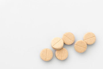 Fototapeta na wymiar Beige a lot of medical pills on white background. The view from the top. Isolated