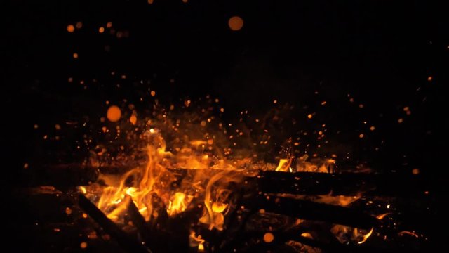 Fire in nature. Bokeh from the fire. Blurred backgrounds. Space views. Sparks are beautifully flying right at you. Shooting speed 60fps, slow motion. Live shooting of the most beautiful flame.