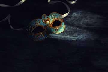 Image of elegant blue and gold venetian, mardi gras mask over black background.