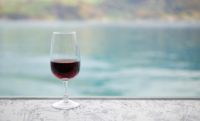 Red wine glass on bar over blur green lake background