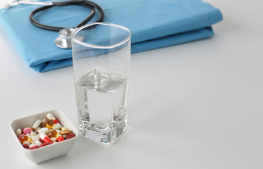 stethoscope a glass of water and pills on a uniform