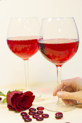 The concept of Love, Wedding, Proposal, Anniversary. Two glasses of red wine, woman's hand holding a glass, close up, light background