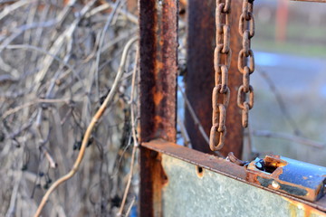 rusty, broken lock and chain, thieves. old rusty lock and a metal chain, bolted on a broken wooden door close-up. In the door panels there are a number of damages, and several bars have been broken.