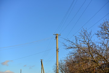 Utility Pole against Blue Sky supporting overhead power lines, electrical cable, fibre optic cable, transformers and street lights.