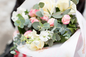 floral arrangement, wedding, surprise concept. close up of bouquet wrapped in white craft paper, it is collected of extremely beautiful and delicate flowers, pink roses and few white ones