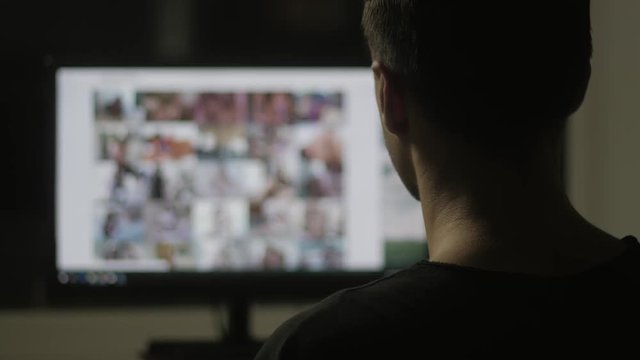 young man watching surfing pornography site on the web at night at home