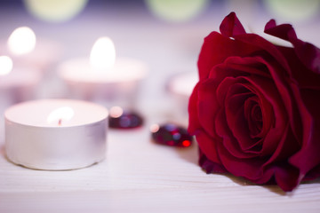 Fototapeta na wymiar The concept of Love, Wedding, Proposal, Anniversary. A romantic evening with burning aroma candles and a beautiful red velvet rose, blurred background, top view