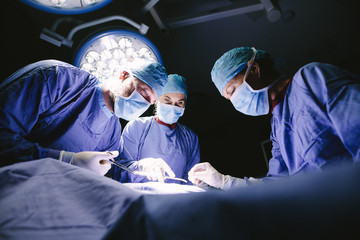 Group of surgeons doing surgery in hospital - obrazy, fototapety, plakaty