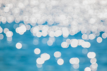 Abstract blurred blue water with shining sunlight bokeh on blue sea